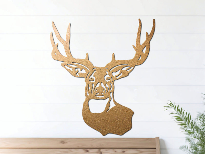 Gold deer head metal wall art hangs on a white wall above a wooden bench