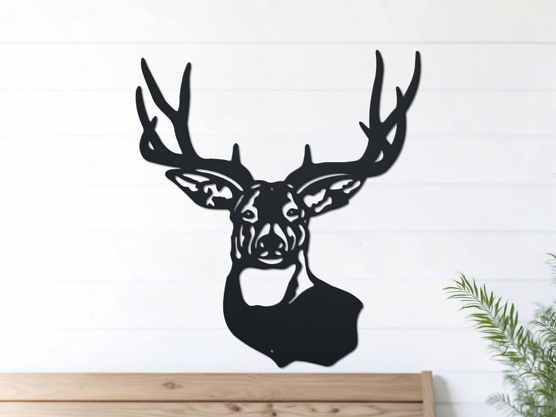 Black deer head metal wall art hangs on a white wall above a wooden bench
